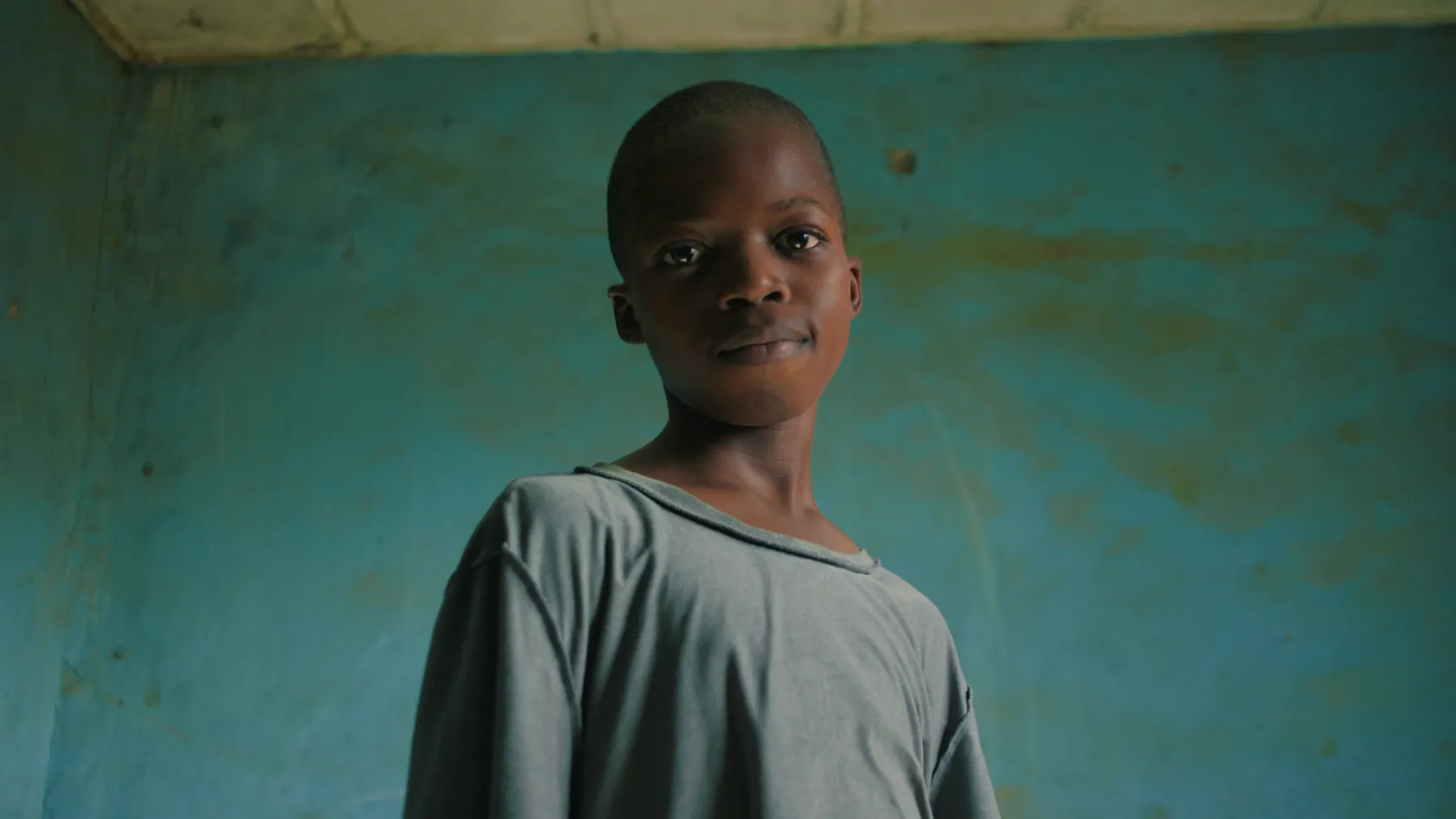 Portrait d'un jeune garçon devant un mur turquoise
